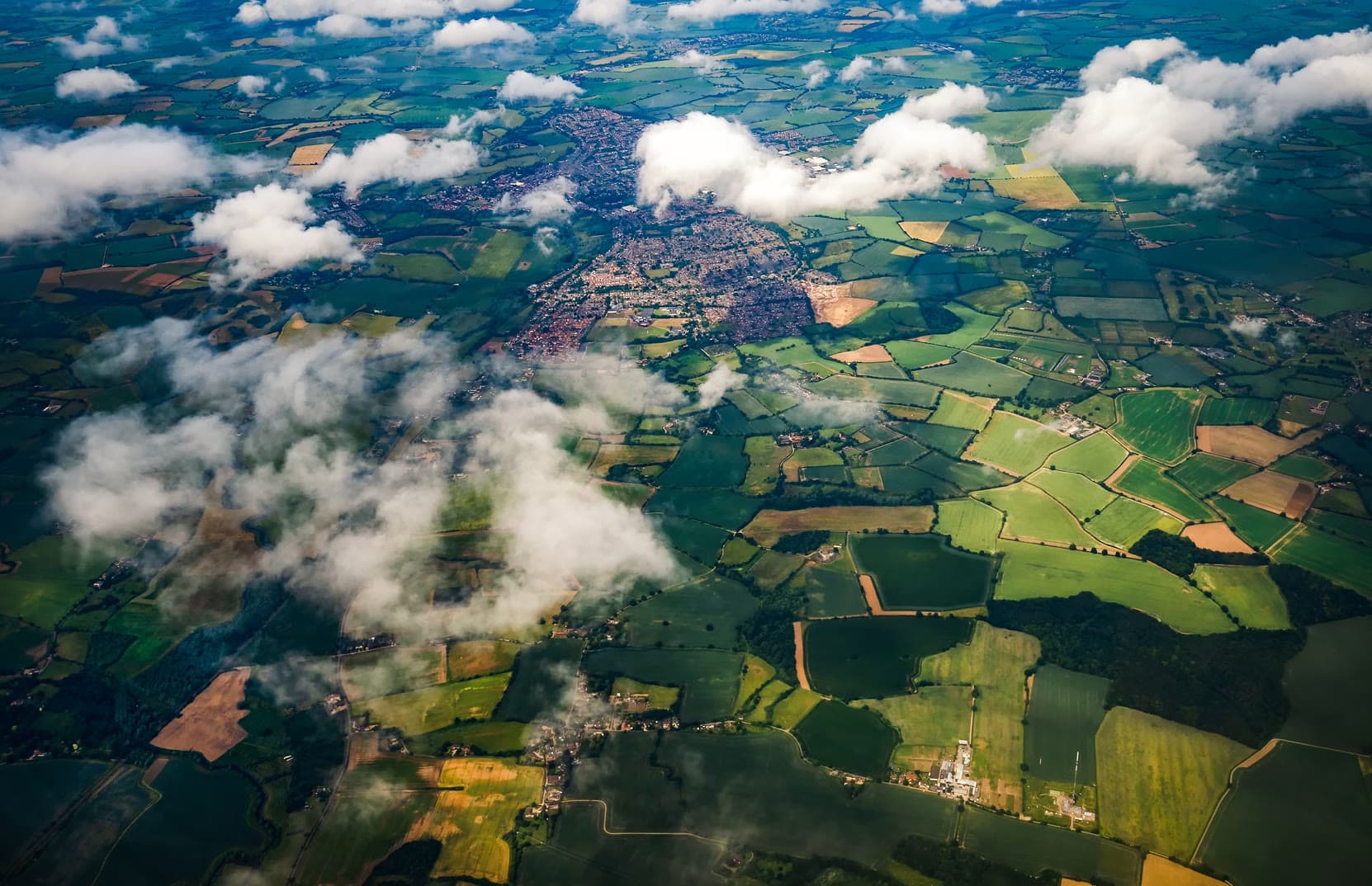 Aerial view of farmland and a town under scattered clouds