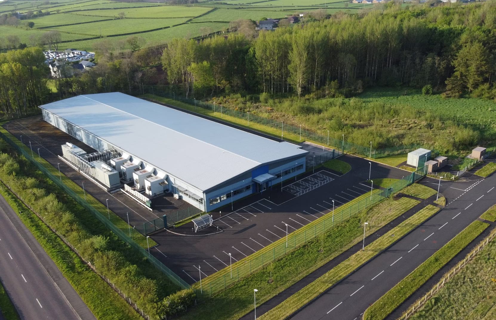 Aerial view of a large industrial building beside a highway